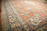 Distressed vintage Persian Mahal carpet featuring pale rust, blue floral sprays, and a prominent palmette finial.