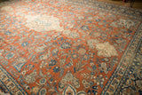 Textured floral sprays and dense scrolling vines in rust, blue, and ivory on vintage Mahal carpet.