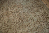 Close-up of a distressed Heriz carpet, showing geometric vinery, low pile, and beige brown tones.