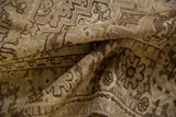 Folded distressed Heriz carpet pile showing geometric patterns in pale brown and antique ivory.