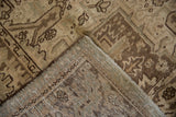 Folded corner of a distressed Heriz carpet, showing low pile, knot heads, and woven foundation.