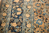 Close-up of distressed Persian Meshed rug, blue and beige floral palmettes, aged texture.