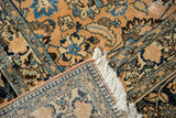 Worn floral pattern, ivory fringe, and woven foundation of a distressed Meshed carpet.