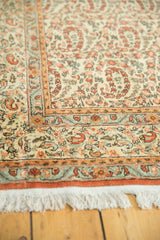 Qom carpet's pale ivory fringe and rust border, with pale blue paisley boteh detail.