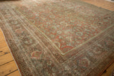 Distressed Mahal rug corner with faded geometric borders and worn palmette motifs.