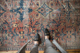 Distressed vintage Mahal carpet with scrolling floral design in brick red, teal, and sand tones.