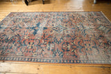Distressed Mahal carpet section showcasing low pile brick red, teal floral pattern.