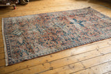 Distressed Mahal carpet, showcasing worn blush red and teal scrolling floral motifs.