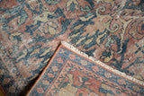 Distressed vintage Mahal rug corner, revealing low pile, faded floral patterns, and blue-red tones.