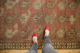 Hand-knotted Afghan runner's stylized boteh motifs, chestnut terracotta field, and geometric border.