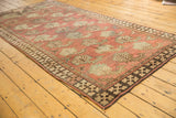 Stylized terracotta boteh motifs and dark geometric border on an antique Afghani rug.