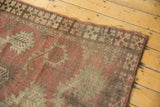 Antique Afghan rug detail: geometric border, stylized boteh, muted terracotta, and chocolate tones.
