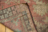 Antique Afghan rug's folded corner showing worn terracotta pile, woven foundation, and dark fringe.