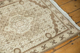 Vintage Bijar rug corner featuring ivory Herati motif field, chocolate arabesque border, fringe.