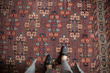 Antique Turkmen carpet's abrashed plum field, featuring guls in madder red, teal, and ivory.