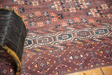 Intricate geometric border and staggered guls on an abrashed aubergine antique Turkmen rug.