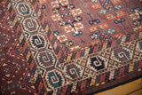 Abrashed aubergine field, staggered guls, and intricate geometric border detail on antique Turkmen rug.