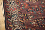 Antique Turkmen carpet detail: geometric border and staggered guls on an aubergine abrashed field.
