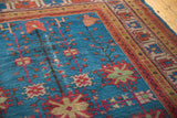 Khotan carpet detail: sapphire blue field with long-stemmed floral palmettes and geometric border.
