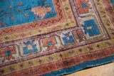 Khotan carpet border with gold, ivory, and cherry red geometric patterns, adjacent to blue floral field.