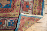 Hand-knotted Khotan carpet's lifted corner, revealing geometric floral pile and woven foundation.