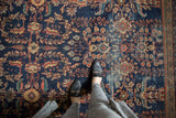 An antique Persian Mahal carpet’s blossomed floral pattern in navy, terra cotta, and oxidized green.