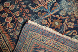 Folded corner of antique Mahal carpet showing navy floral field, low pile, terra cotta border, and fringe.
