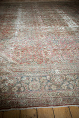 Distressed Mahal rug edge: worn copper-terracotta pile, henna plant motif, exposed foundation.