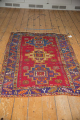Vintage Turkish rug detail: cherry red field, serrated main border, and colorful floral motifs.