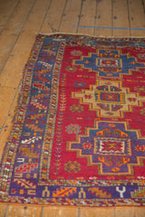 Vintage Turkish rug's corner, featuring serrated border and royal blue stepped medallion on cherry red field.