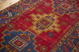 Cherry red vintage Turkish rug with geometric stepped medallions, floral motifs, and low pile.