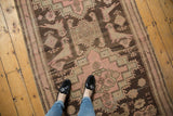 Distressed Karabagh runner showing faded blush rose and charcoal brown floral and bird motifs.