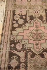 Distressed Karabagh runner detail: pale rose florals on worn charcoal brown field.