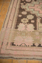 Antique Karabagh runner corner revealing distressed pale blush rose and charcoal patterns with wear.