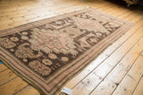 Distressed corner of antique Karabagh runner, with charcoal, blush, and seafoam geometric motifs.