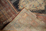 Folded antique Afshar rug reveals hand-knotted foundation, worn pile, and geometric design.