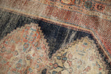 Sharply serrated navy blue field on antique Afshar rug, with sand, red, blue motifs, knot wear.