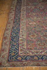 Antique Malayer rug featuring intricate navy and beige borders surrounding a plum floral field.