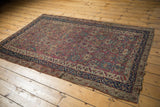 Antique Malayer rug: intricate plum floral design with low pile and worn navy borders.