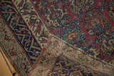 Folded corner of antique Malayer rug, revealing floral panels, woven foundation, and low pile wear.