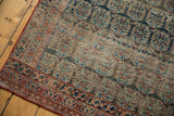 Antique Heriz rug's worn pile texture, revealing knot heads and intricate boteh design.
