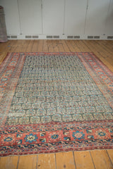 Angled antique fragment Heriz carpet, repeating boteh pattern in navy, sky blue, coral border.
