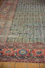 Antique Heriz carpet showing blush-red, navy border and charcoal boteh field motifs.