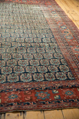 Antique Heriz carpet's intricate red border with blue floral motifs and navy boteh field.