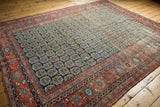 Antique Heriz carpet showcasing an allover navy boteh field and terracotta borders.