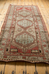 Distressed end of a Vintage Serab runner, featuring a red reciprocating pawn border and secured fringe.