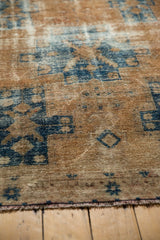 Distressed vintage Hamadan rug detail with worn sand field, faded navy geometric patterns.