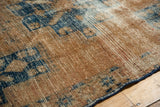 Distressed Hamadan rug pile, revealing etched foundation in sand and navy blue.