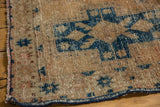 Distressed texture revealing navy geometric motifs on the sand field of a vintage Hamadan rug.
