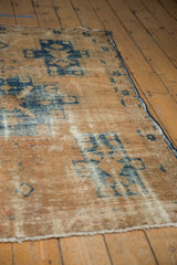 Distressed vintage Hamadan rug texture with worn sand and navy blue pile.